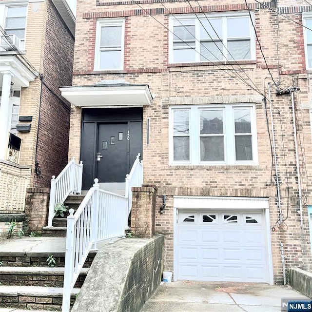 150 W 29th, Bayonne, NJ 07002 - doorway to property featuring brick siding, a garage, and concrete driveway