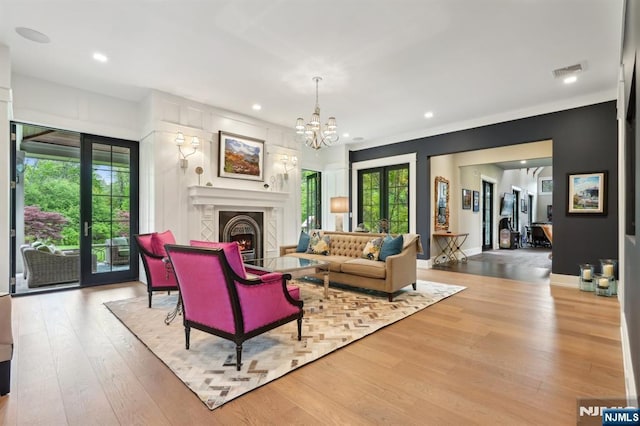 living area with wood finished floors, recessed lighting, a chandelier, a lit fireplace, and baseboards