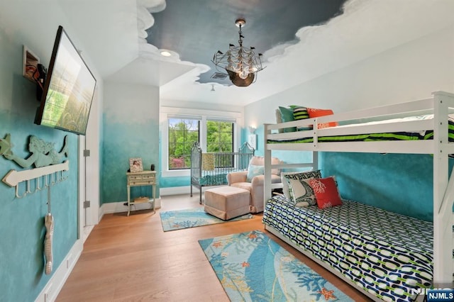 bedroom with a chandelier, wood finished floors, and baseboards
