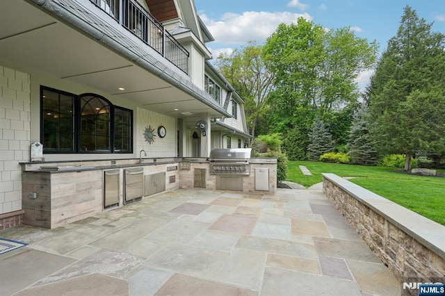 view of patio / terrace with grilling area, an outdoor kitchen, a sink, and a balcony