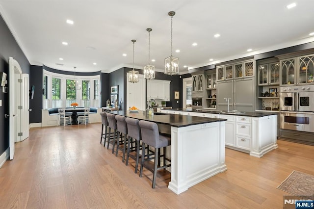 kitchen with a large island, dark countertops, stainless steel double oven, open shelves, and recessed lighting