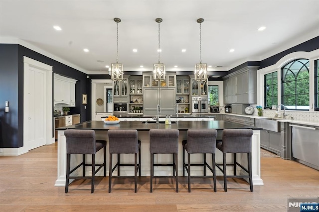 kitchen featuring a sink, dishwasher, hanging light fixtures, a kitchen breakfast bar, and recessed lighting