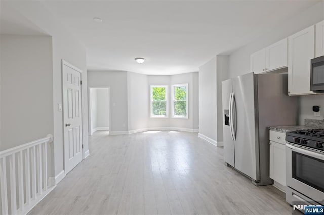 kitchen featuring stainless steel appliances, white cabinets, light wood-style floors, open floor plan, and baseboards