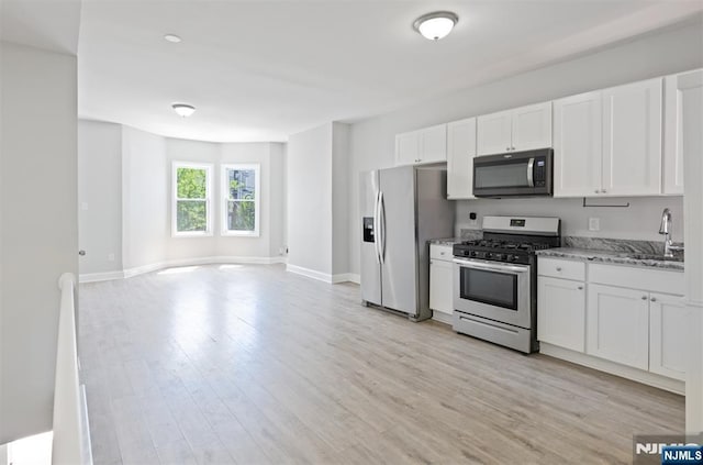 kitchen featuring stainless steel appliances, a sink, white cabinetry, and light wood-type flooring