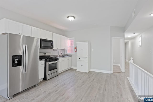 kitchen featuring stainless steel appliances, white cabinetry, and light wood finished floors