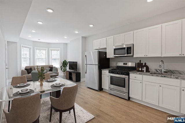 kitchen featuring stainless steel appliances, a sink, white cabinets, light stone counters, and recessed lighting