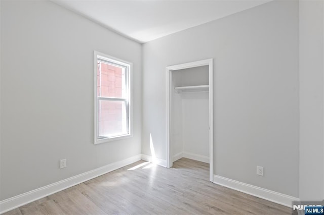 unfurnished bedroom featuring wood finished floors, baseboards, and a closet