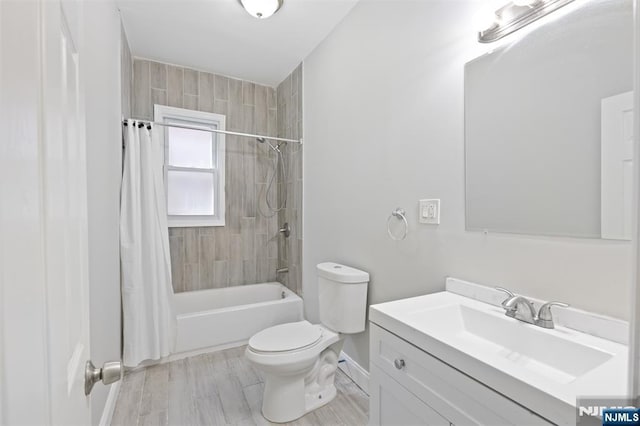 bathroom featuring toilet, baseboards, shower / bath combo with shower curtain, vanity, and wood finished floors