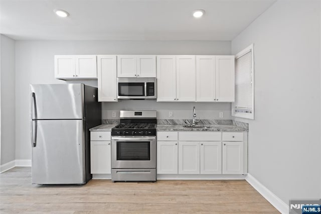 kitchen featuring stainless steel appliances, a sink, white cabinetry, baseboards, and recessed lighting