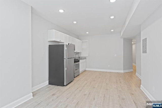 kitchen featuring appliances with stainless steel finishes, white cabinets, a sink, light wood-type flooring, and recessed lighting