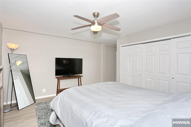 bedroom featuring light wood-style flooring, baseboards, a ceiling fan, and a closet