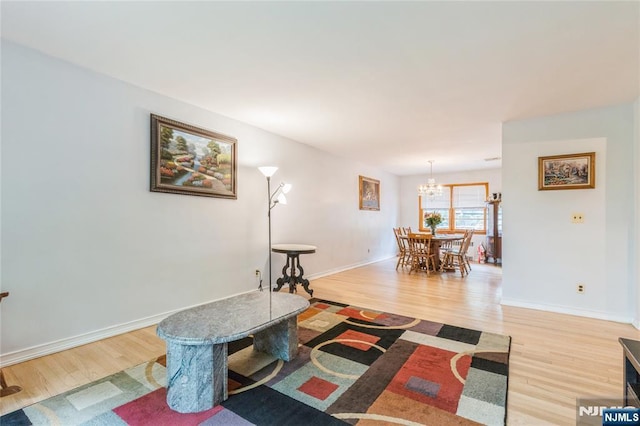living room featuring light wood finished floors, a chandelier, and baseboards