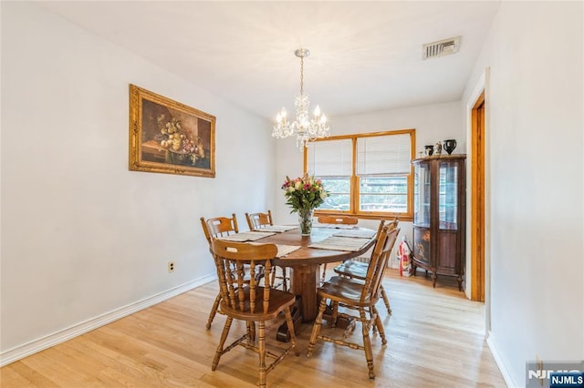 dining area with a chandelier, light wood finished floors, and baseboards