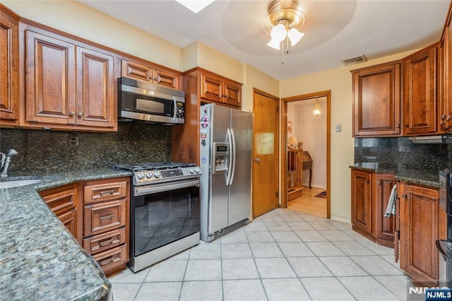 kitchen with appliances with stainless steel finishes, ceiling fan, tasteful backsplash, a sink, and light tile patterned floors
