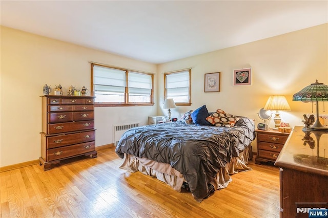 bedroom featuring radiator heating unit, light wood-type flooring, and baseboards