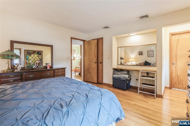 bedroom featuring light wood finished floors, ensuite bathroom, and baseboards