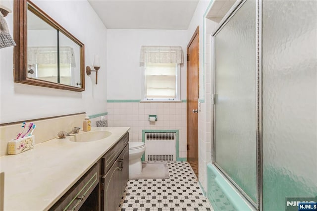 full bath featuring radiator, tile walls, a shower with door, toilet, and tile patterned floors