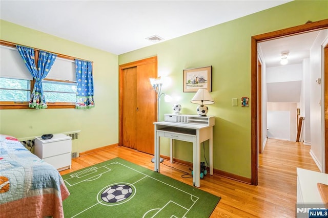 bedroom featuring wood finished floors, baseboards, and a closet