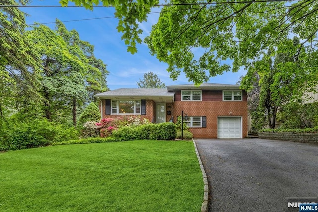 split level home featuring driveway, brick siding, a front lawn, and an attached garage
