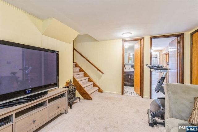 living area featuring light carpet, stairs, and baseboards