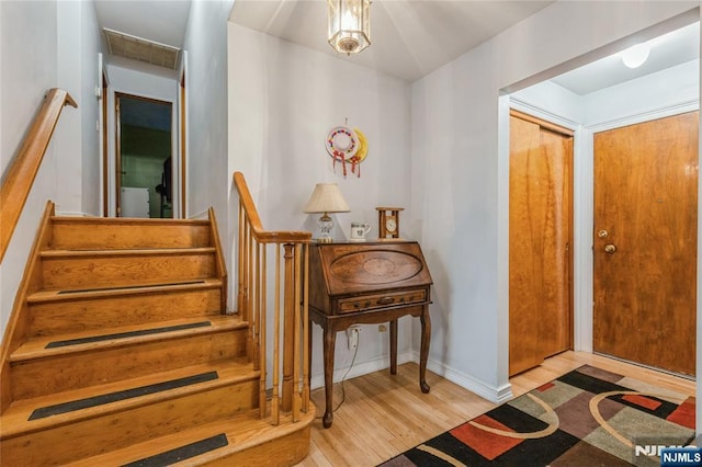 foyer with wood finished floors, stairway, and baseboards