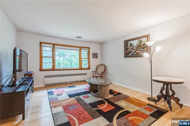 living area with radiator heating unit, wood finished floors, and baseboards