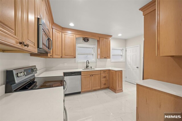 kitchen with appliances with stainless steel finishes, a sink, recessed lighting, light marble finish floors, and light countertops
