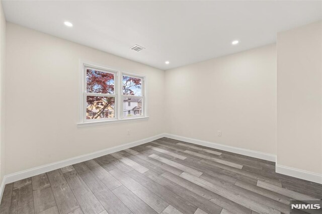 spare room featuring wood finished floors, baseboards, and recessed lighting