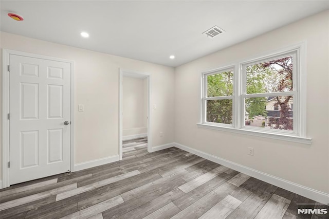 unfurnished bedroom featuring baseboards, wood finished floors, and recessed lighting