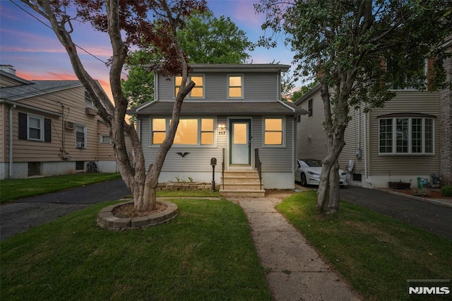 traditional style home featuring entry steps, a yard, and asphalt driveway