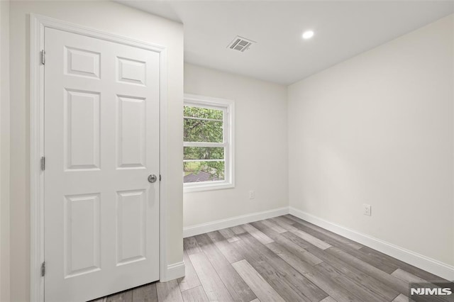 spare room featuring wood finished floors, baseboards, and recessed lighting