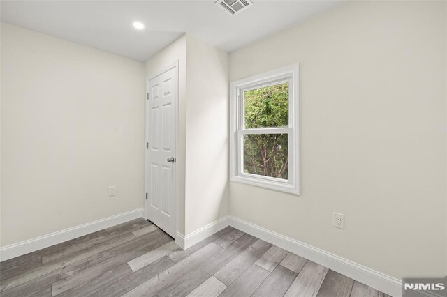 unfurnished room featuring wood finished floors, baseboards, and recessed lighting