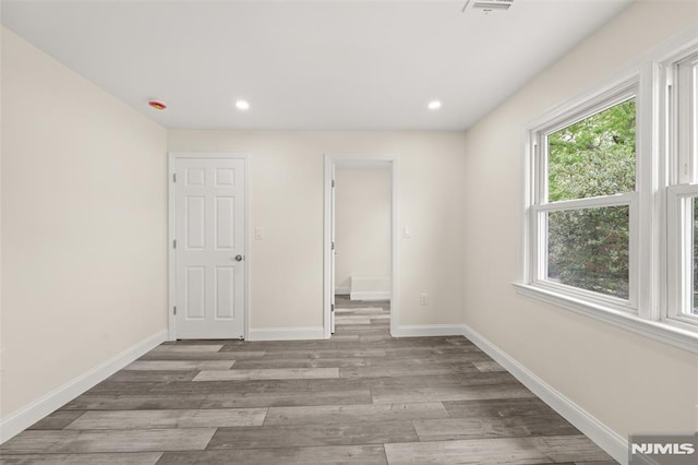spare room with wood finished floors, baseboards, recessed lighting, and a smoke detector