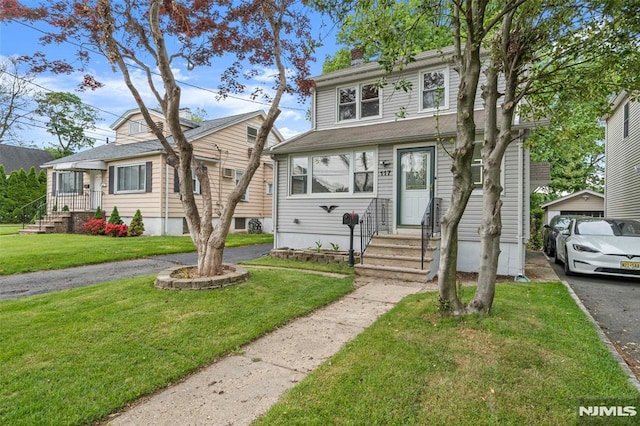 view of front of home with entry steps, a front yard, and a chimney