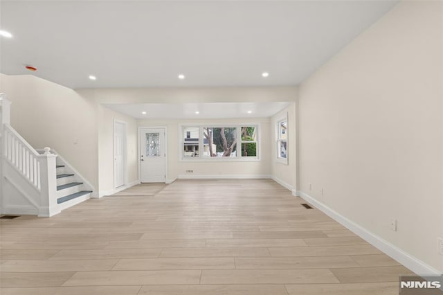 unfurnished living room featuring light wood-type flooring, stairs, recessed lighting, and baseboards