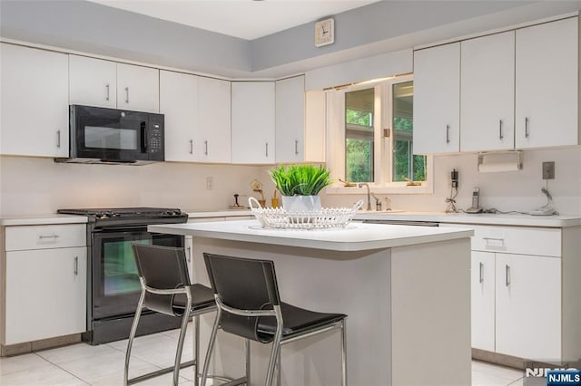 kitchen featuring black appliances, light countertops, a kitchen breakfast bar, a kitchen island, and light tile patterned floors