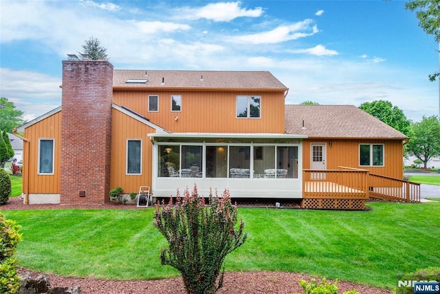 rear view of property featuring a sunroom, a chimney, a lawn, and roof with shingles