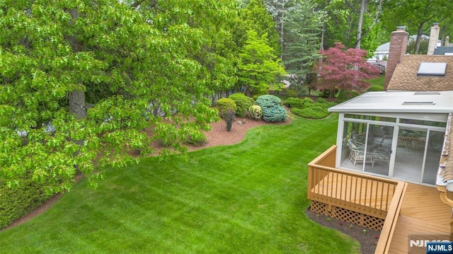 view of grassy yard with a sunroom and a deck