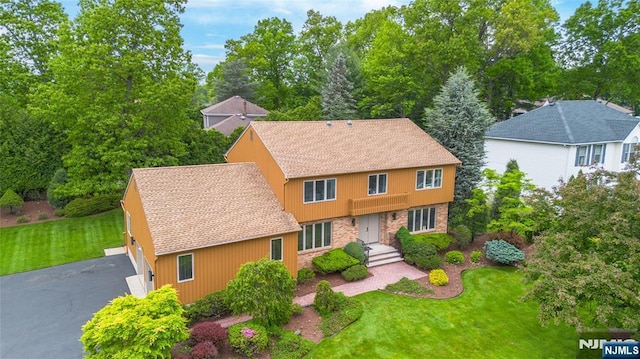 view of front facade featuring a front lawn, driveway, and roof with shingles