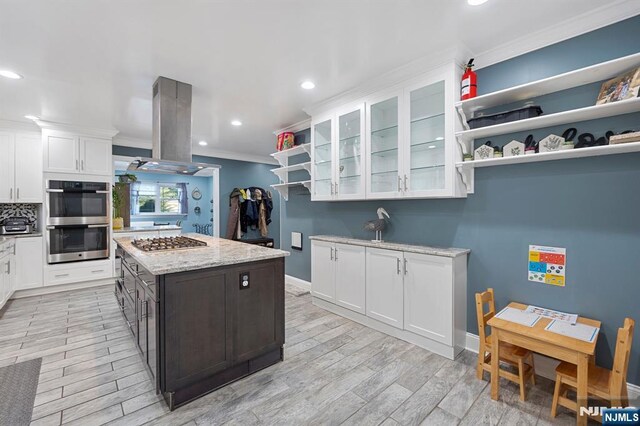 202 Elmwynd Dr, Orange, NJ 07050 - kitchen with stainless steel appliances, ornamental molding, white cabinetry, light wood finished floors, and glass insert cabinets