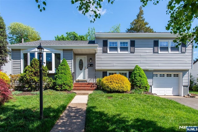 split level home with a front lawn, a garage, and driveway