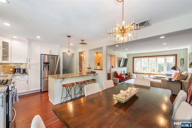 dining space with dark wood-style floors, recessed lighting, and a chandelier