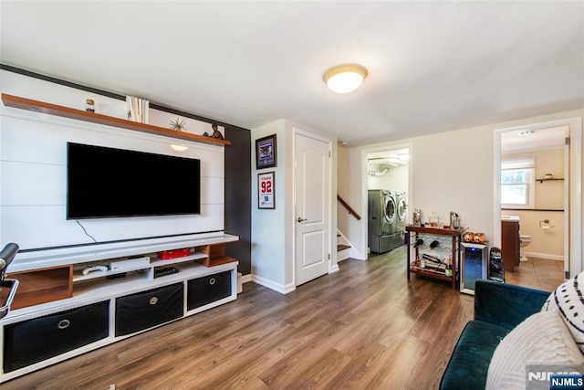 living area featuring washing machine and dryer, stairway, wood finished floors, and baseboards