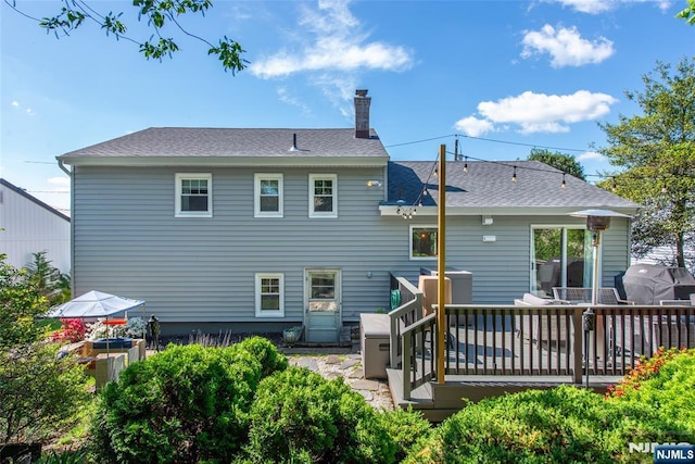 back of house with a chimney and a deck