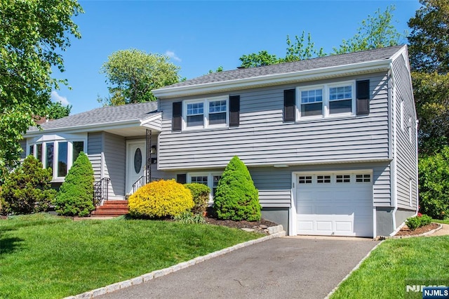 split level home with a front lawn, a garage, and driveway