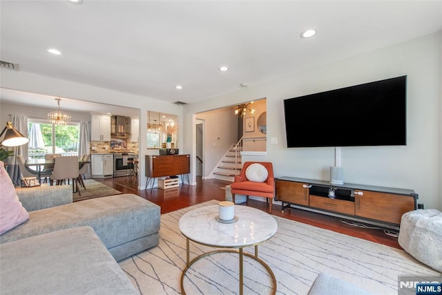 living room featuring a chandelier, wood finished floors, stairway, and recessed lighting