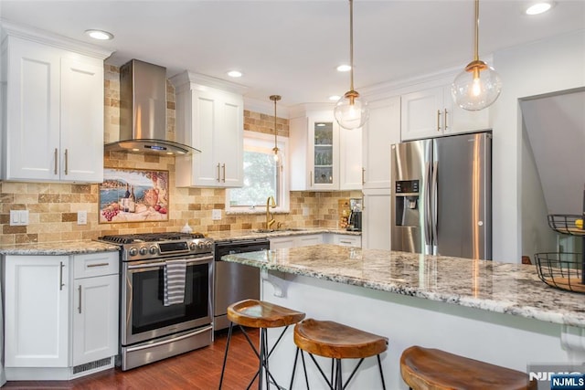kitchen featuring stainless steel appliances, wall chimney exhaust hood, a sink, white cabinets, and dark wood finished floors