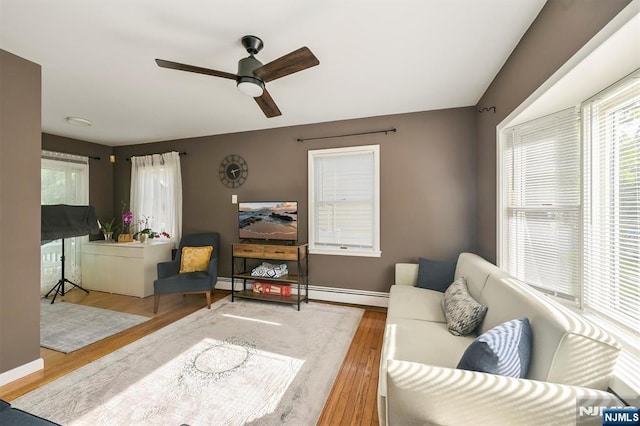 living room with wood finished floors, ceiling fan, baseboards, and a baseboard radiator
