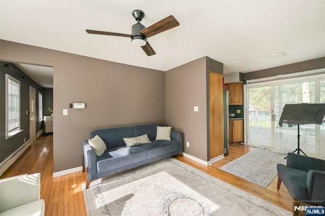 living area with light wood-style flooring, a ceiling fan, baseboards, and baseboard heating