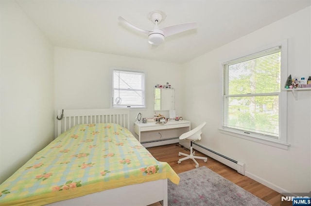 bedroom featuring baseboard heating, wood finished floors, and a ceiling fan